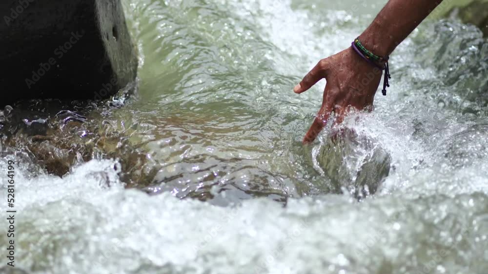 A Black Hands Touching the Flow of Water in the River