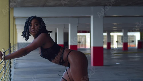 Lingerie model close up as an African girl is bent over the railing of a parking garage photo