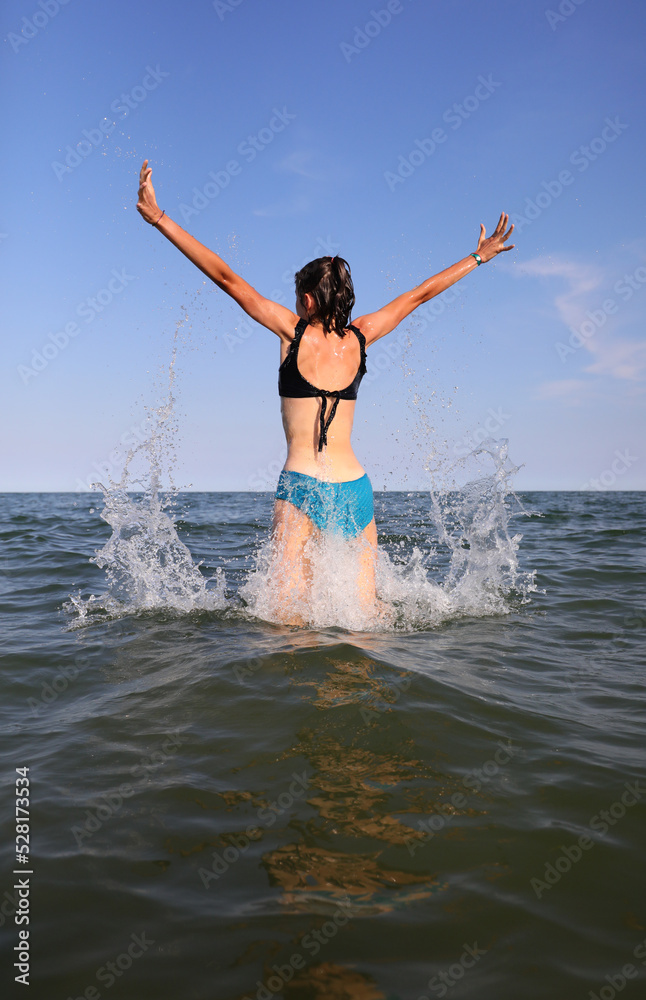 girl jumping out of the sea water exulting with joy and happiness