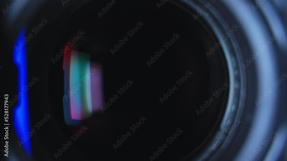 Close-up black professional camcorder transfocation zoom lens with hood and color reflections. High quality 4k footage