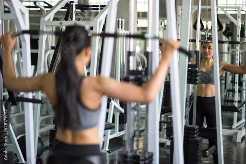 Sporty Asian woman exercise with lat pulldown machine in gym