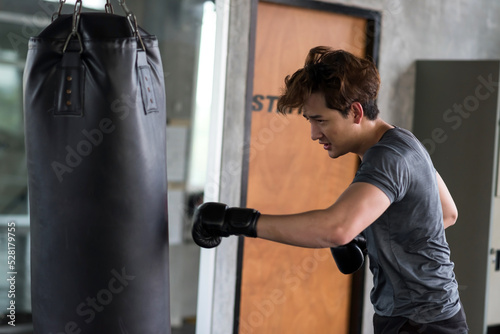Handsome young boxer punching big bag at fitness gym © Blanscape