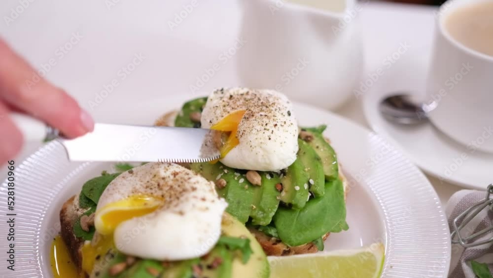 healthy breakfast or snack - woman cutting a poached egg healthy breakfast or snack - woman cutting a poached egg