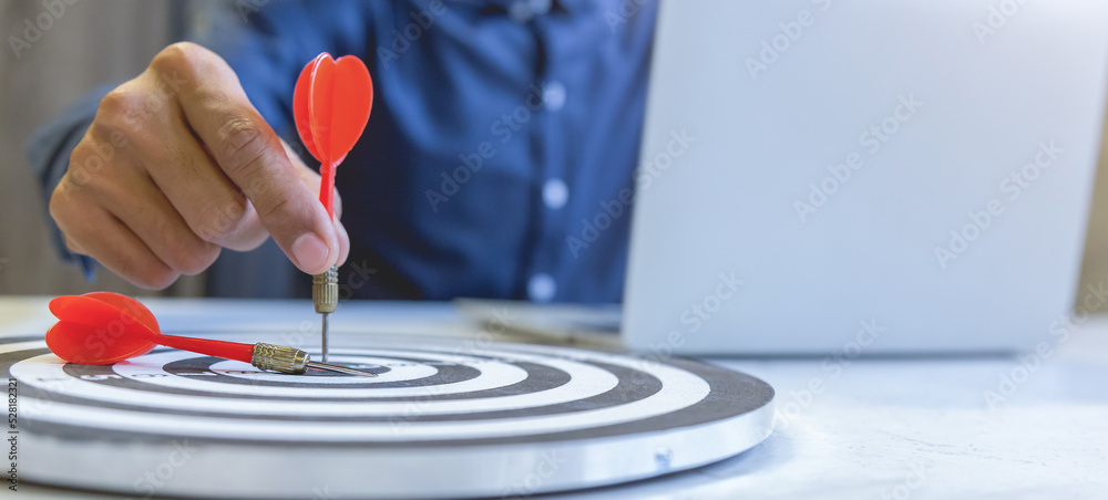 Businessman holding a darts aiming at the target center,business growth success concept. Businessman holding a darts aiming at the target center,business growth success concept.