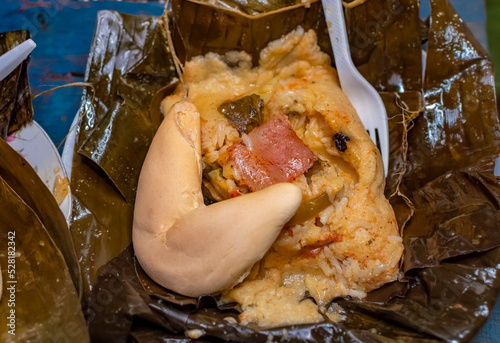 Nacatamal served with bread in a banana leaf on the table. Traditional Nacatamal served in banana leaf, Nicaraguan Nacatamal with bread on the table, Traditional Venezuelan Hallaca served photo