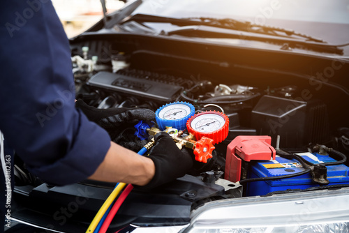 Close up hand of auto mechanic are to use measuring manifold gauge for filling car air conditioners. Concepts of fix and checking for repair service , Car service concept .