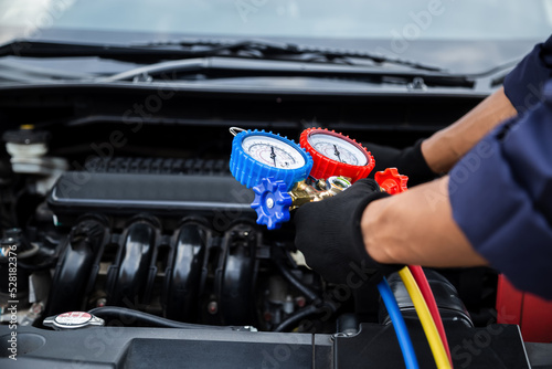 Close up hand of auto mechanic are to use measuring manifold gauge for filling car air conditioners. Concepts of fix and checking for repair service , Car service concept .