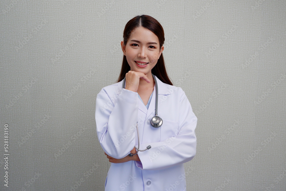 Beautiful Asian female doctor standing smiling happy to show pride or success with a stethoscope on the shoulder wearing a white medical gown. Beautiful Asian female doctor standing smiling happy to show pride or success with a stethoscope on the shoulder wearing a white medical gown.
