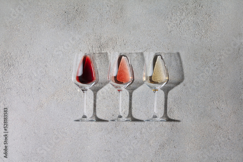 Fototapete Flat-lay of red, rose and white wine in glasses on grey stone background