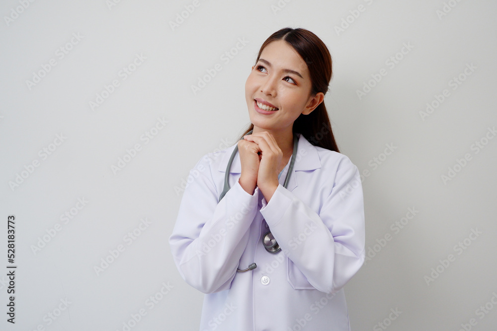 Beautiful Asian female doctor standing smiling happy to show pride or success with a stethoscope on the shoulder wearing a white medical gown. Beautiful Asian female doctor standing smiling happy to show pride or success with a stethoscope on the shoulder wearing a white medical gown.