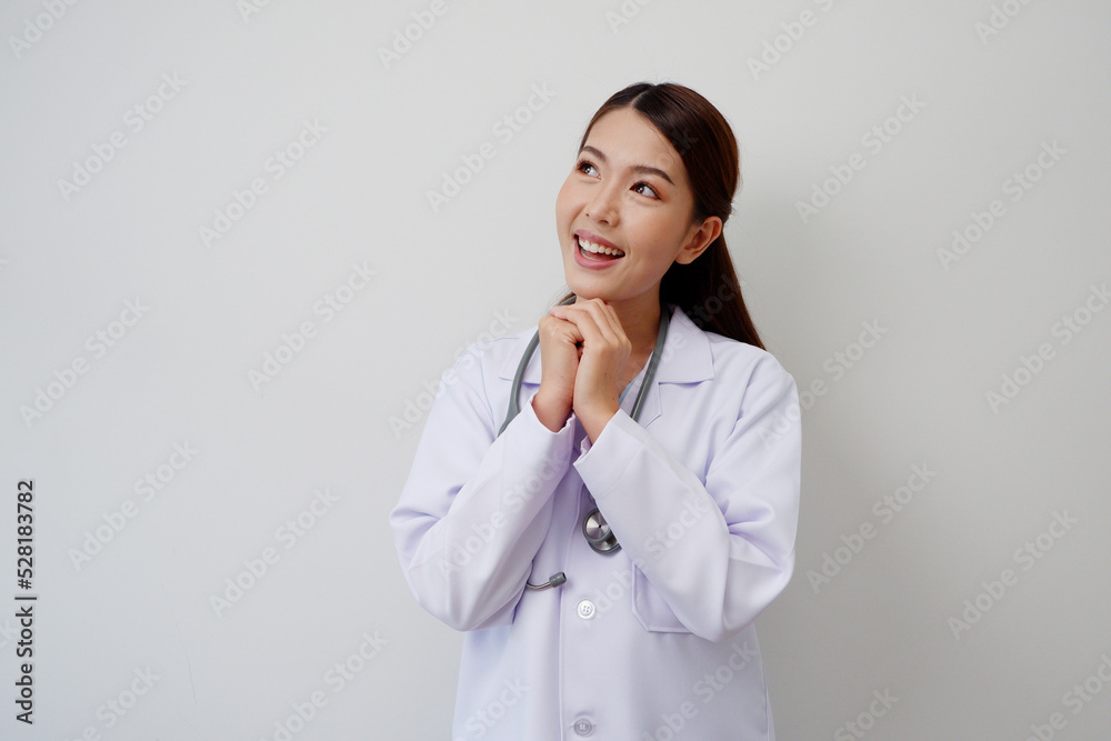 Beautiful Asian female doctor standing smiling happy to show pride or success with a stethoscope on the shoulder wearing a white medical gown. Beautiful Asian female doctor standing smiling happy to show pride or success with a stethoscope on the shoulder wearing a white medical gown.