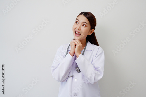 Beautiful Asian female doctor standing smiling happy to show pride or success with a stethoscope on the shoulder wearing a white medical gown.