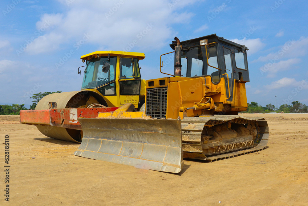 bulldozer and road roller with yellow color, on construction site and sky background