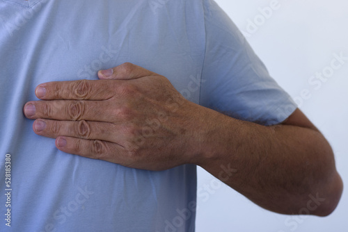 A man feeling chest pain. He is having a serious pain on chest. Close up shot of hands holding left part of chest. Healthcare concept, A man has severe heart pain and chest pain suffocating.