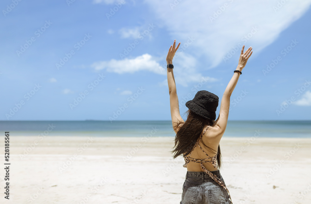 woman wearing black bowler on her head and wear a back short pants stand on the beach on sunny day