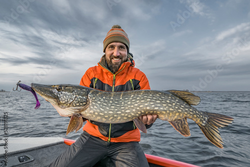 Successful pike fishing. Happy fisherman hold huge muskie fish photo