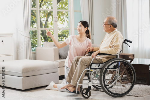 senior with beautiful daughter, old man sitting on wheelchair in house, take care elderly patient and be friends at home.