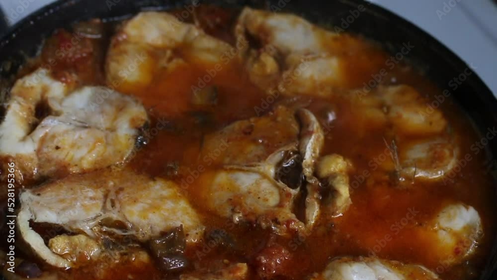 The man removes the lid from the pan. Pieces of fish in fried vegetables are stewed in a frying pan. Stew fish with vegetables. Puts the lid back on. Close-up shot of hands. The man removes the lid from the pan. Pieces of fish in fried vegetables are stewed in a frying pan. Stew fish with vegetables. Puts the lid back on. Close-up shot of hands.