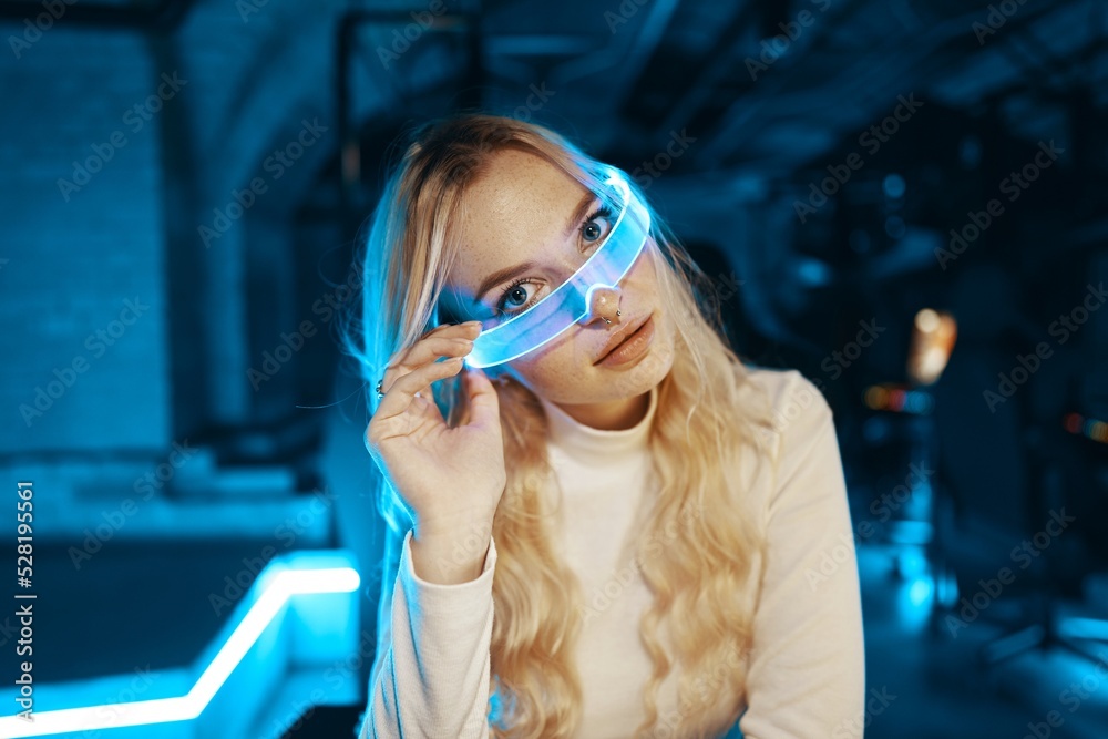 Young woman puts on neon 3d virtual reality glasses.