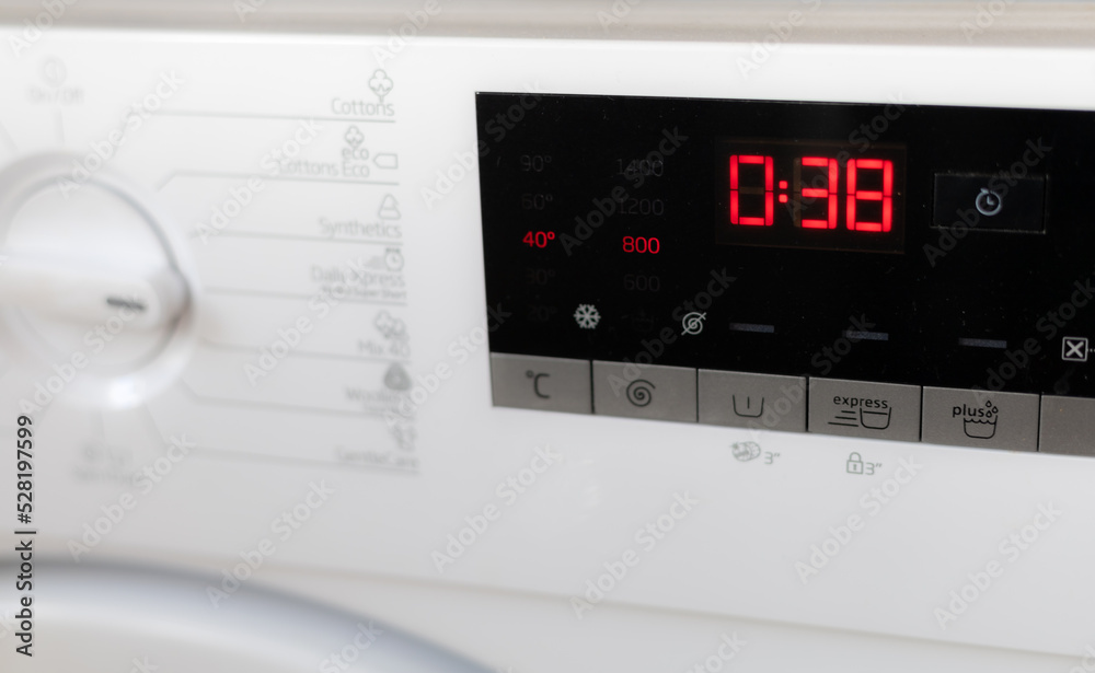 Modern white washing machine front panel with black display.
Modern white washing machine front panel with black display.