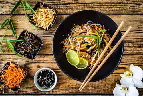 Asian food - konjac noodles, stir fried vegetables, soy sauce and mushrooms on wooden table
 photo