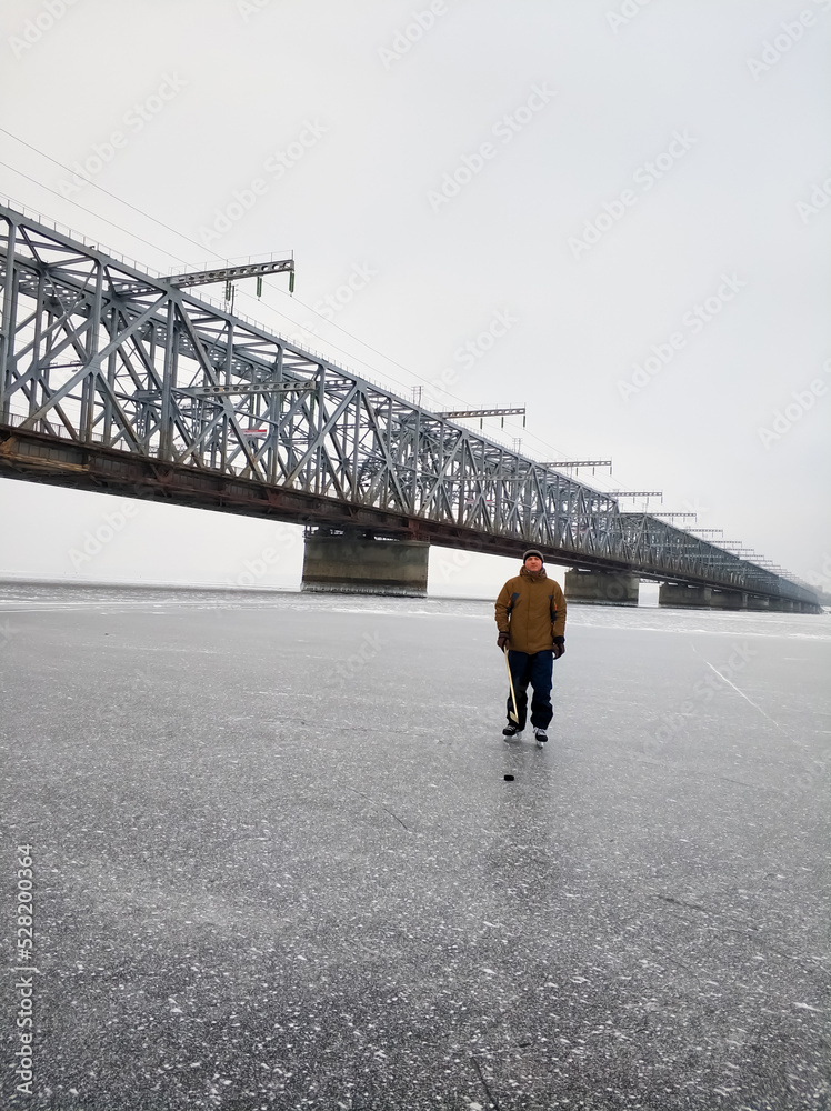 Hockey player on the Volga River the backdrop of a large bridge in Ulyanovsk. Hockey player on the Volga River the backdrop of a large bridge in Ulyanovsk.