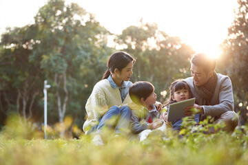 happy asian family having a good time outdoors in city park