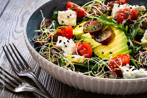 Fresh salad - manouri cheese, avocado, grapes and green vegetables on wooden table
 photo