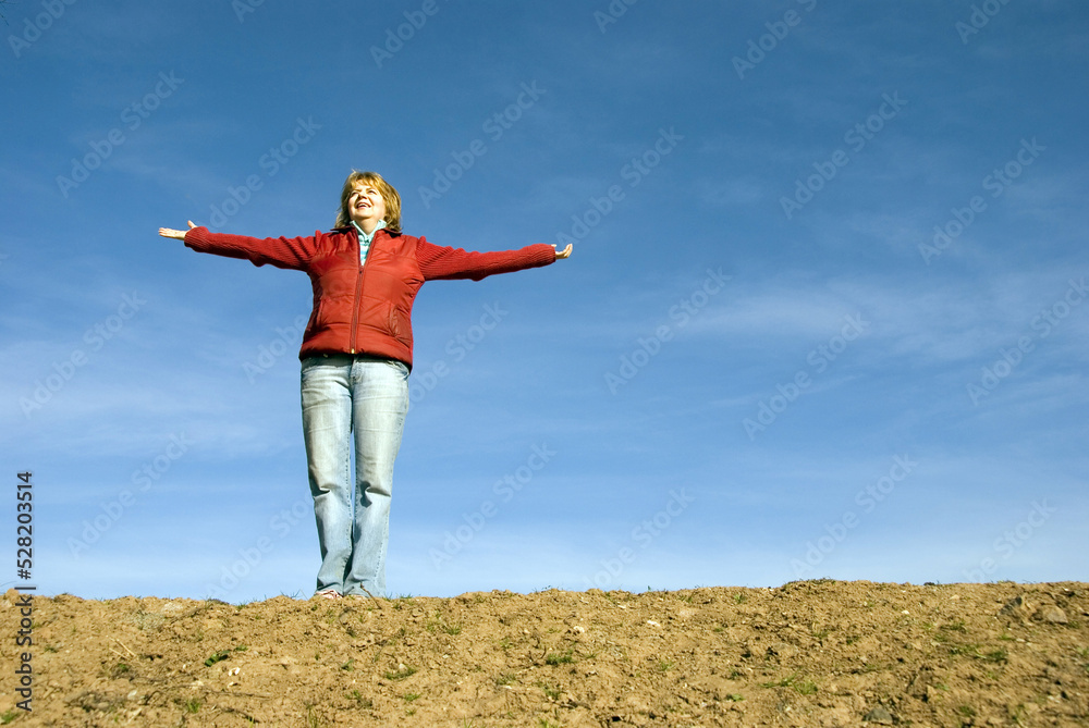 woman in red with open arms in a meadow with blue sky behind. I'm happy! concept woman in red with open arms in a meadow with blue sky behind. I'm happy! concept