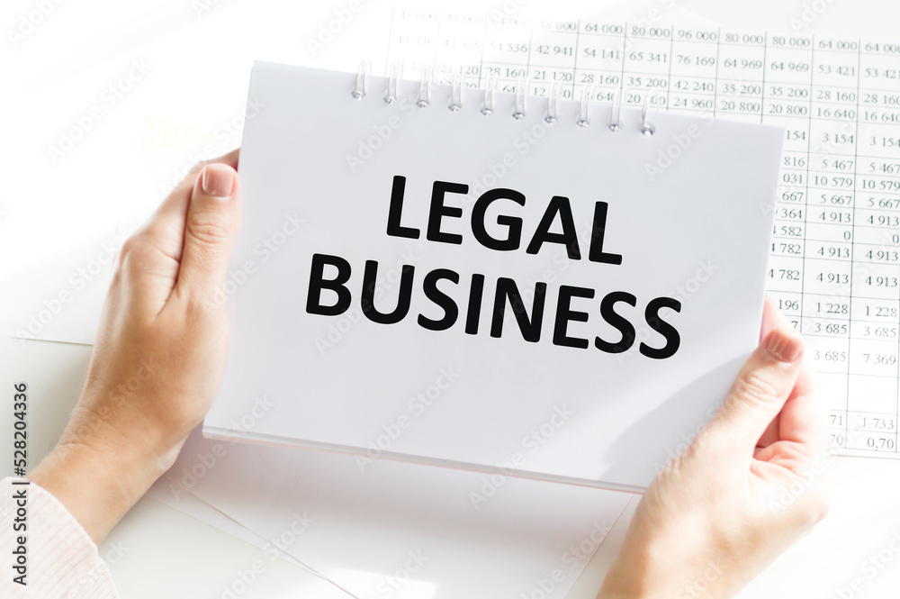 Businessman holding notepad on desktop background with text Legal business Businessman holding notepad on desktop background with text Legal business