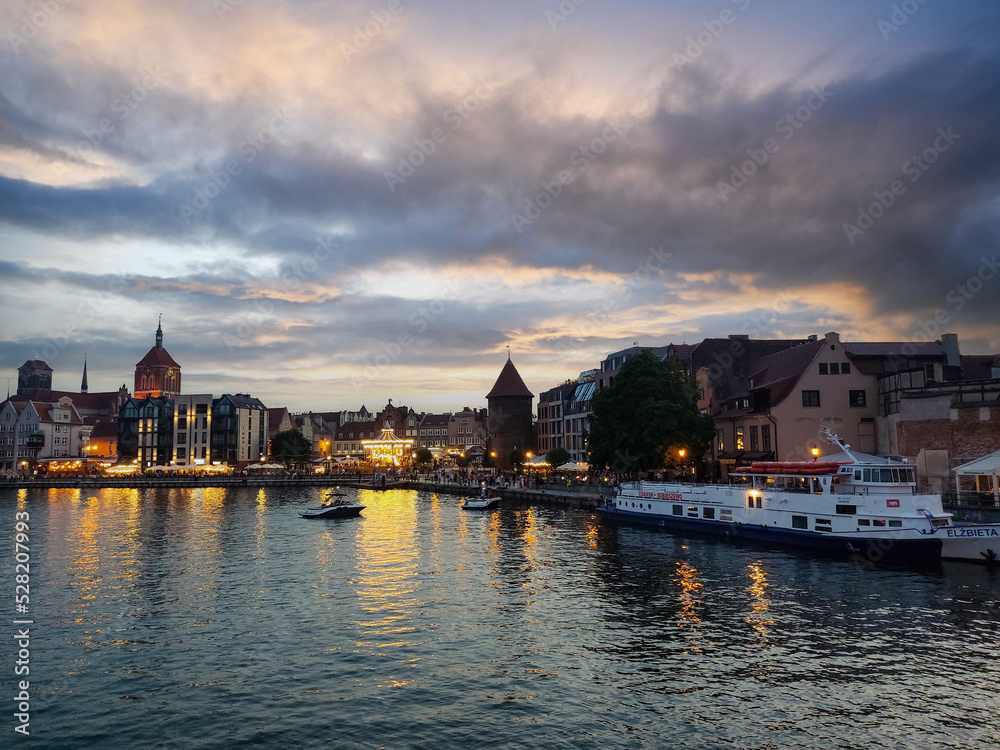 Fototapeta premium Beautiful Gdansk City Reflected in the Motlawa River With the Ferry and Ferris Wheel at Dusk. Poland Summer Evening
