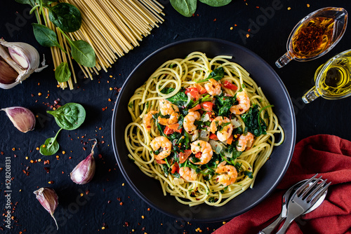 Spaghetti with prawns and spinach on wooden table 
