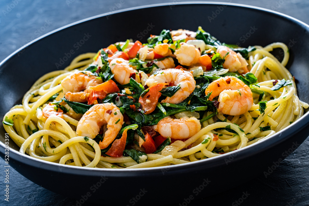 Spaghetti with prawns and spinach on wooden table
