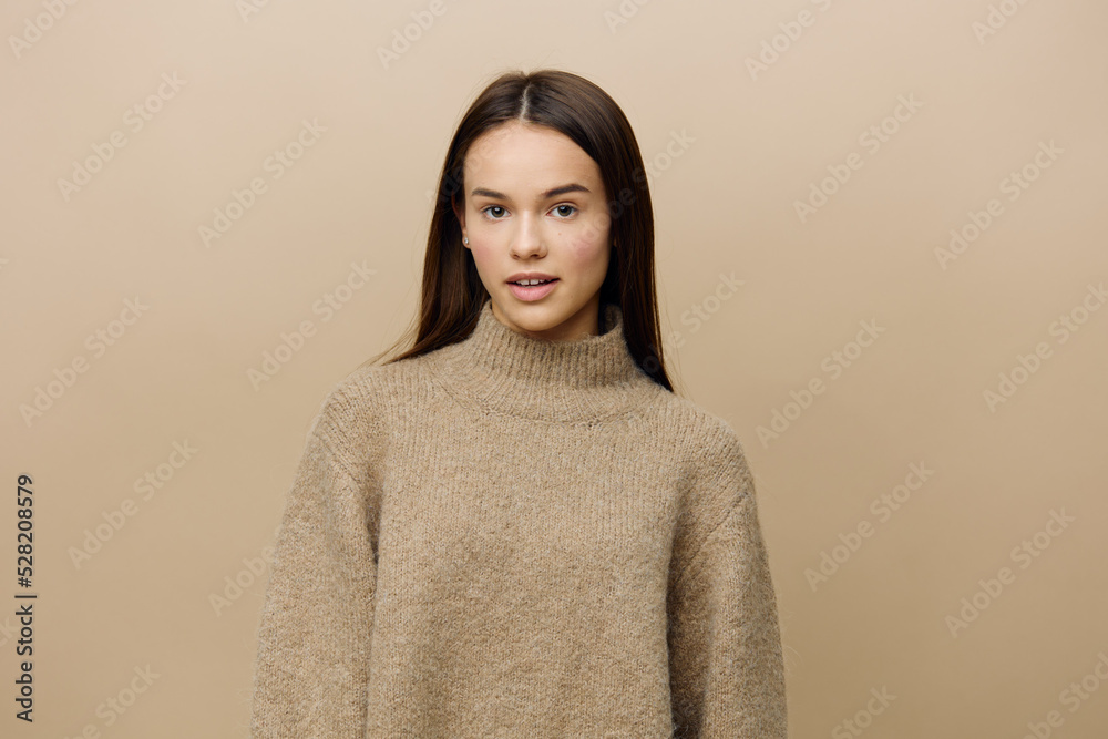 horizontal photo of a beautiful, attractive, relaxed woman in a warm, textured, autumn sweater looking pleasantly into the camera standing on a beige background horizontal photo of a beautiful, attractive, relaxed woman in a warm, textured, autumn sweater looking pleasantly into the camera standing on a beige background