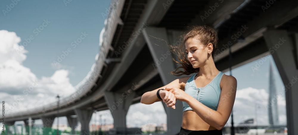 Smart watch on the arm for training, a sporty woman doing fitness exercises on the street