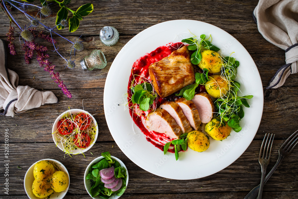 Fried pork loin with boiled potatoes and fresh vegetables on wooden table
Fried pork loin with boiled potatoes and fresh vegetables on wooden table