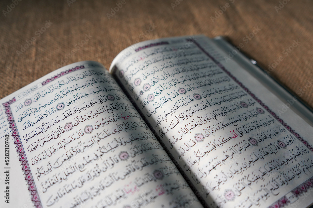 Fototapeta premium Kudus, Indonesia - August, 2022 : The Quran, also romanized Qur'an or Koran, is the central religious text of Islam, believed by Muslims to be a revelation from God (Allah). Brown sack background.