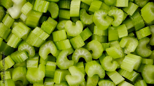 Cutting celery in plate. Pieces of juicy raw chopped celery. Chef cooking vegan salad with raw healthy vegetables