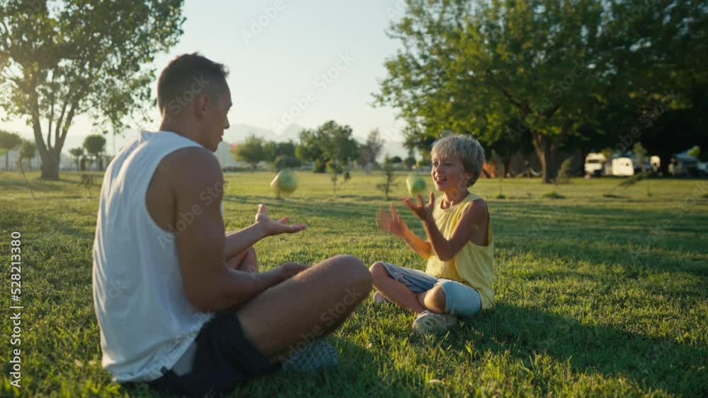 family, leisure and people concept - happy father juggling apples and son learning. Father and son having picnic at summer park. High quality 4k footage family, leisure and people concept - happy father juggling apples and son learning. Father and son having picnic at summer park. High quality 4k footage