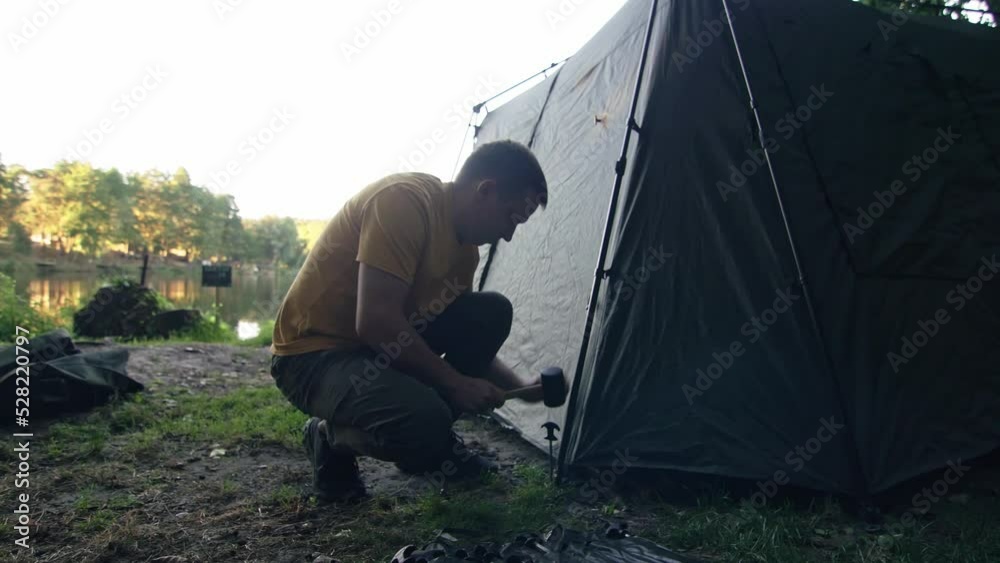 Man installing camping tent near the lake Man installing camping tent near the lake