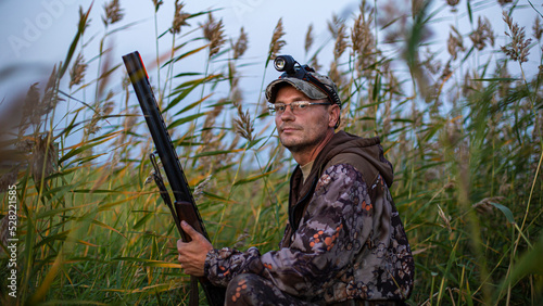 a hunter hiding in the reeds on a wild hunt, waiting for the flight of birds, the background is blurred