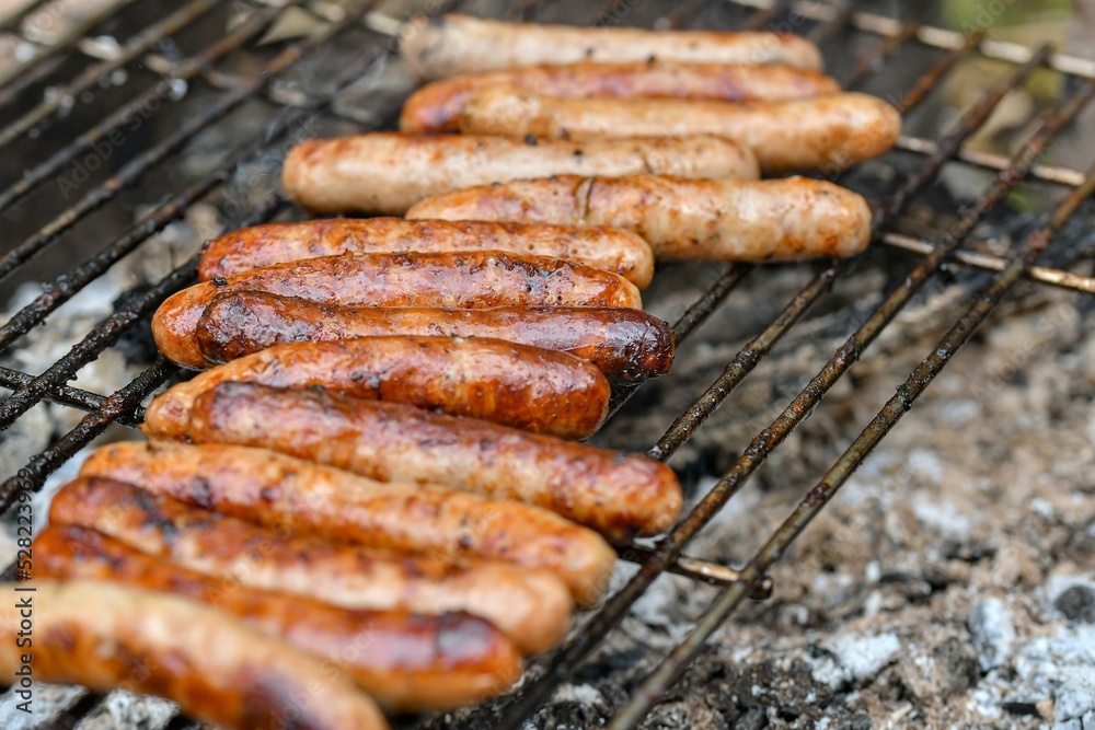 Grilled juicy sausages cooked on a campfire outdoors.