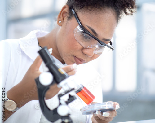 Scientist, chemist woman working in medical research laboratory experimenting chemistry liquid in beaker tube. African American student doctor studying, analyzing sample chemical in pharmaceutical lab