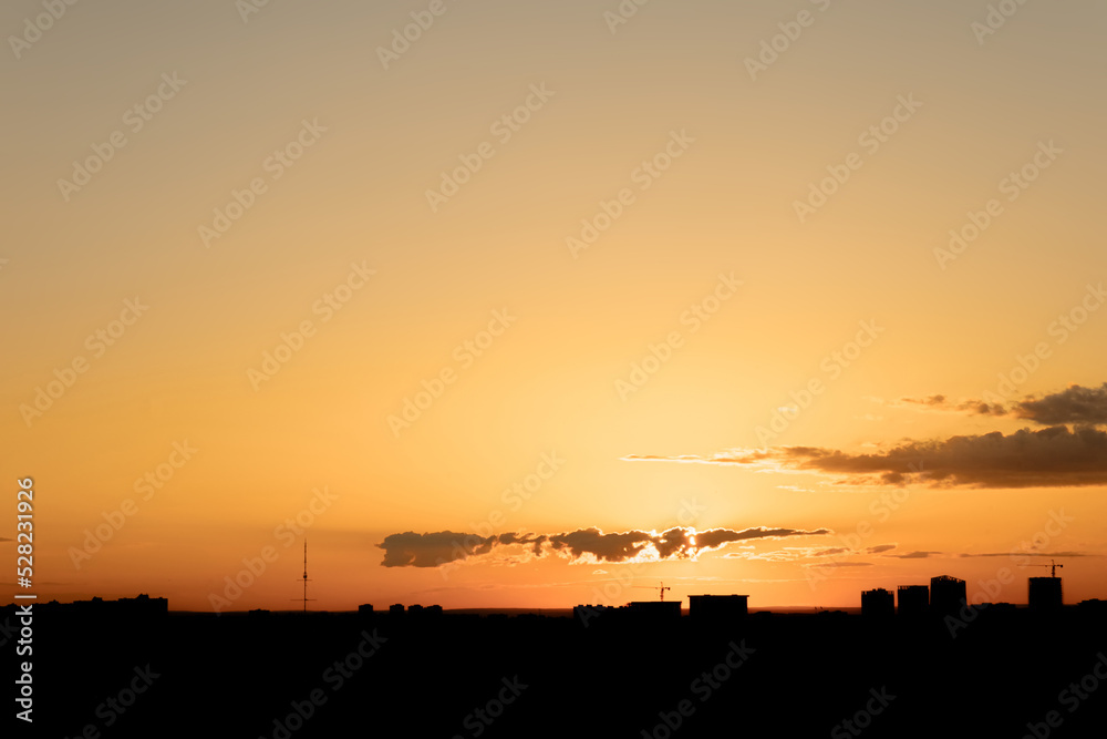 Orange sunset over dark city skyline