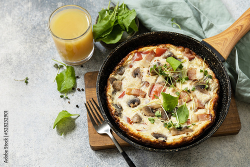 Italian breakfast dish. Rustic omelette (frittata) with mushrooms and bacon on a cast iron pan. Copy space.