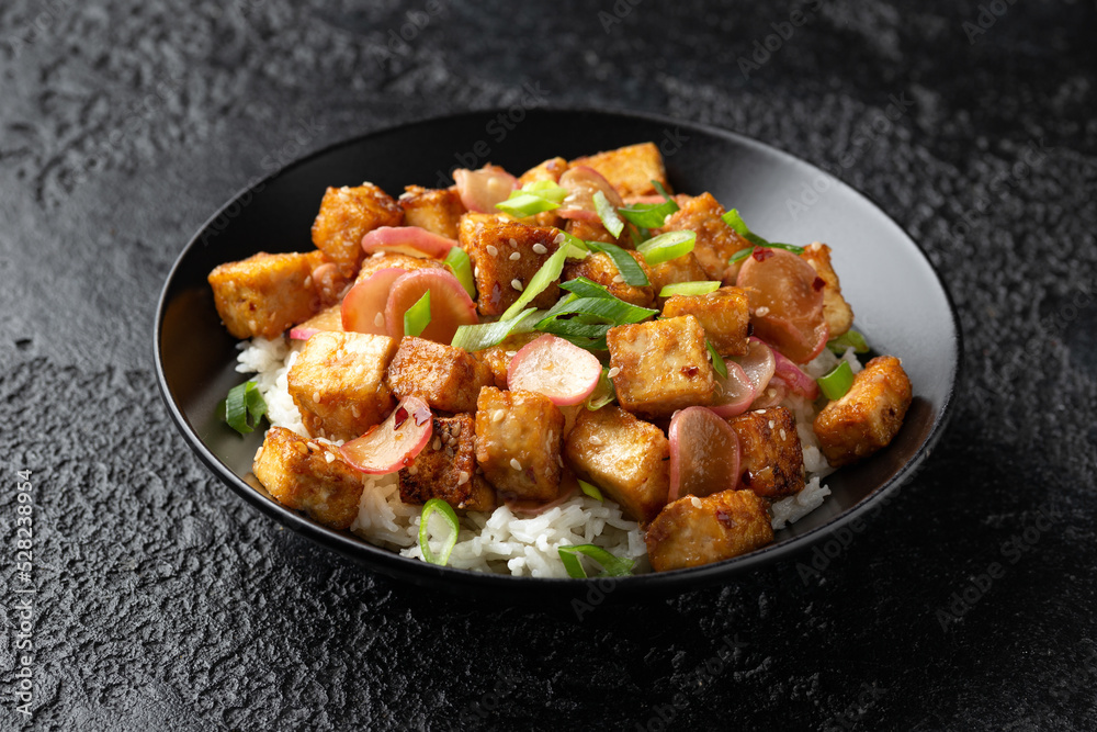 Fried tofu with radish, spring onion and garlic, ginger dressing in black bowl