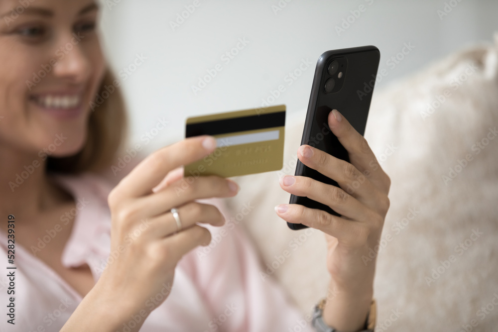 Happy millennial cellphone user woman using credit card, inserting data, buying on internet store website, paying for online purchase, using bank ecommerce app, service. Close up, cropped shot