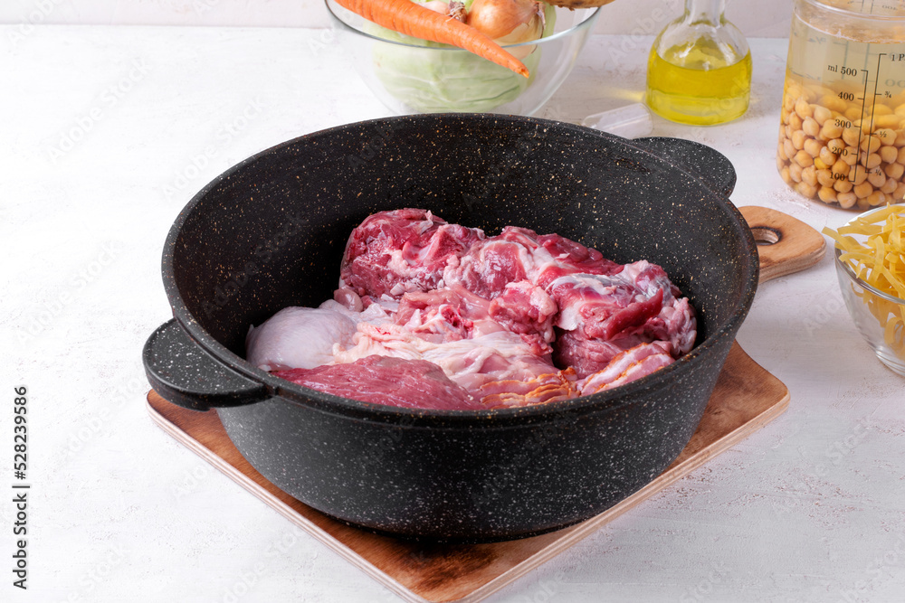 Assorted raw meat in cooking pan. Ingredients for preparing stew, potage, terrine or aspic Assorted raw meat in cooking pan. Ingredients for preparing stew, potage, terrine or aspic