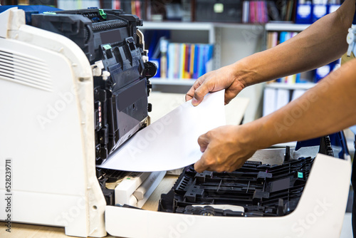 Technician hand open cover photocopier or photocopy to fix copier paper jam and replace ink cartridges for scanning fax or copy document in office workplace.