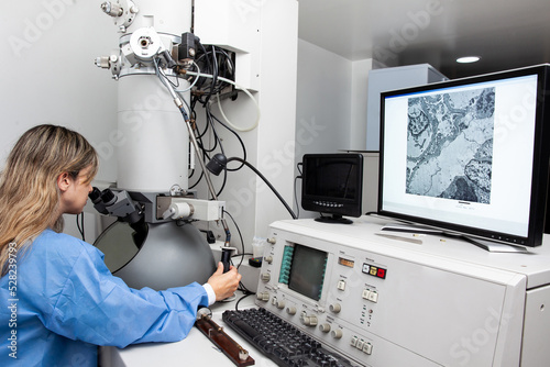 Young female scientist working at the laboratory with an electron microscope